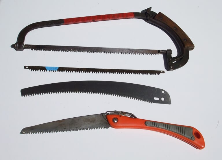 Several pruning saws laid side by side, from a bow saw to a Japanese-style folding saw