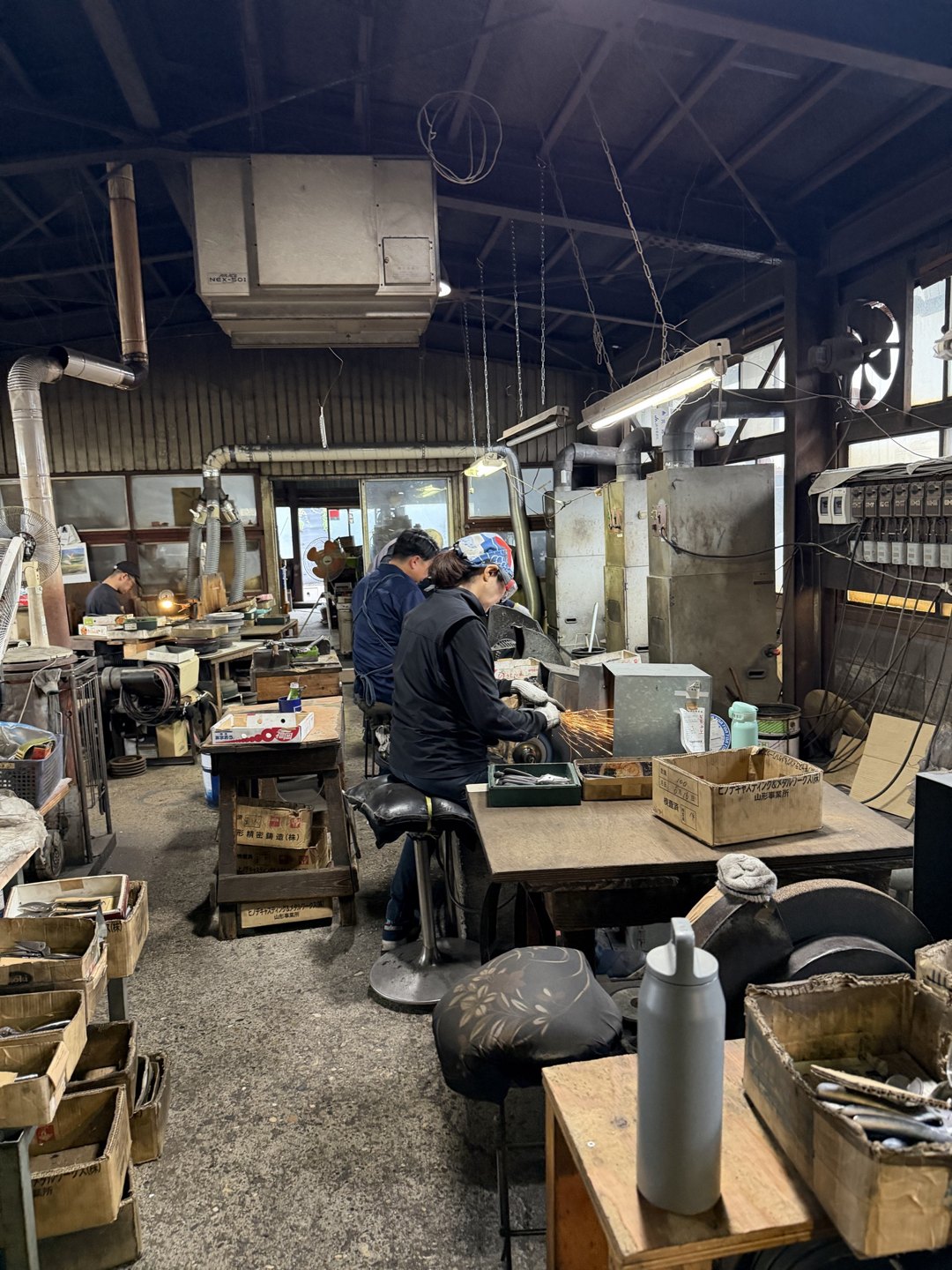 Craftspeople at benches along the long workshop