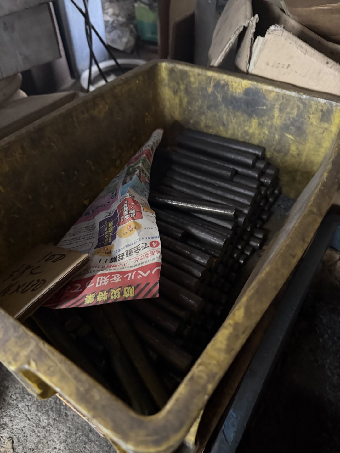 A yellow bin of dark steel bars