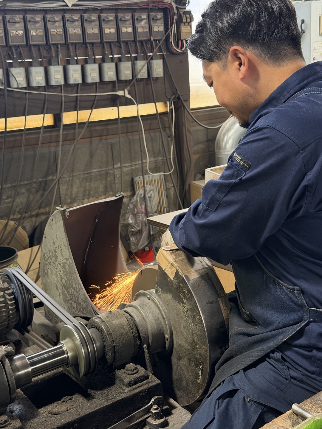 A craftsperson grinding at a wheel with sparks flying