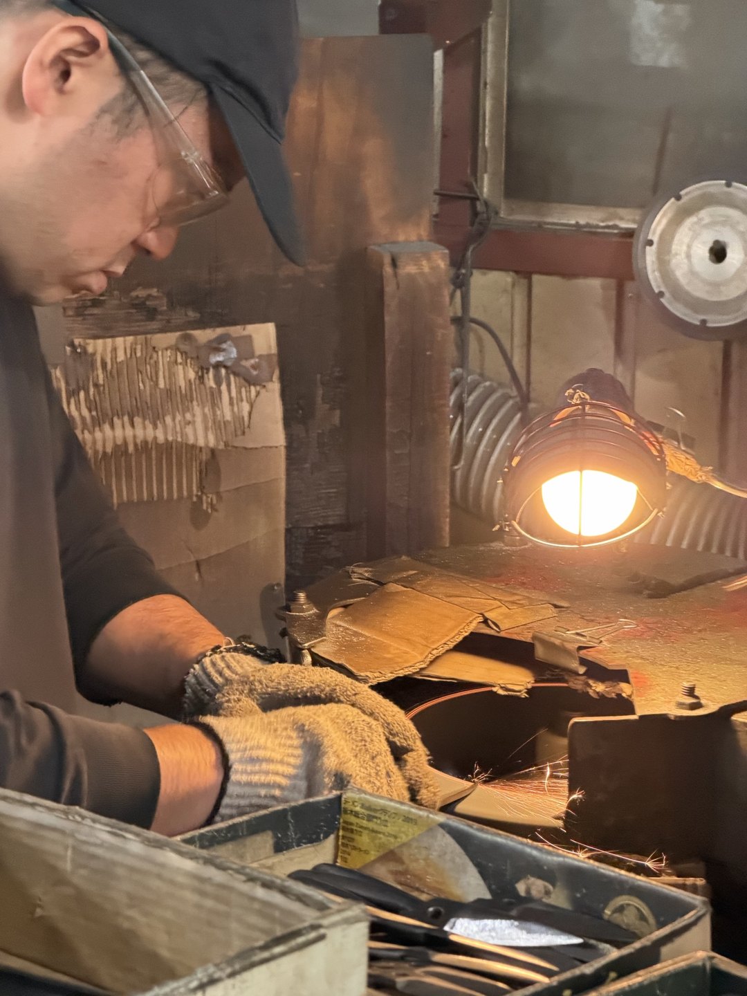 A craftsperson in a cap working under a lamp