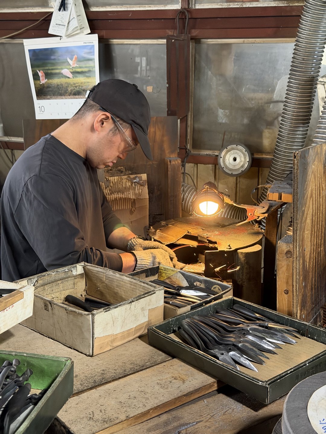 A craftsperson at a bench with boxes of parts