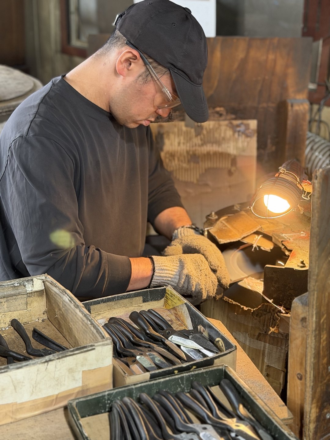 A craftsperson bent over a bench under a lamp