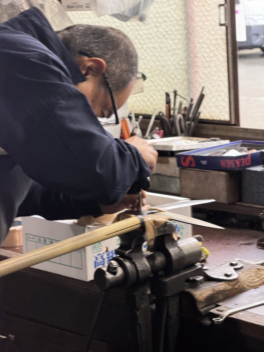 A craftsperson working at a bench vise