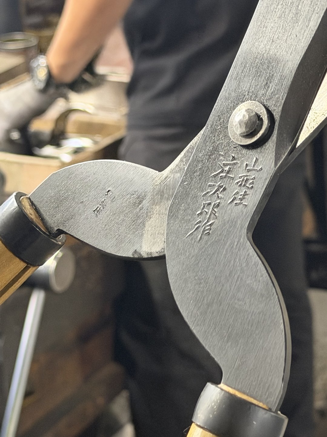 The mark cut into a trimming shear blade, with a craftsperson behind